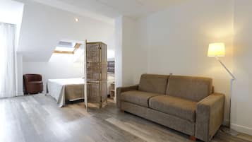 Un salon moderne avec un canapé, une lampe, un fauteuil et un lit.