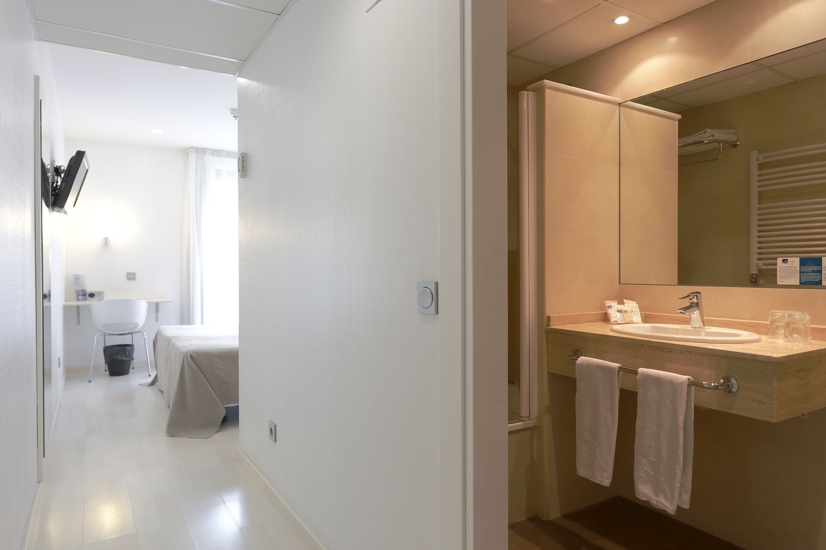 A modern bathroom with a sink, mirror, and towel rack.