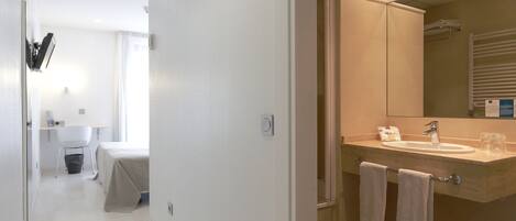 Un baño moderno con lavamanos, espejo y toallero.