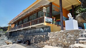A building with a thatched roof, a balcony, and a sign reading "Welcome to Balangan Paradise Sunset Warning." - Balangan Paradise Hostel and Restaurant (Jimbaran)