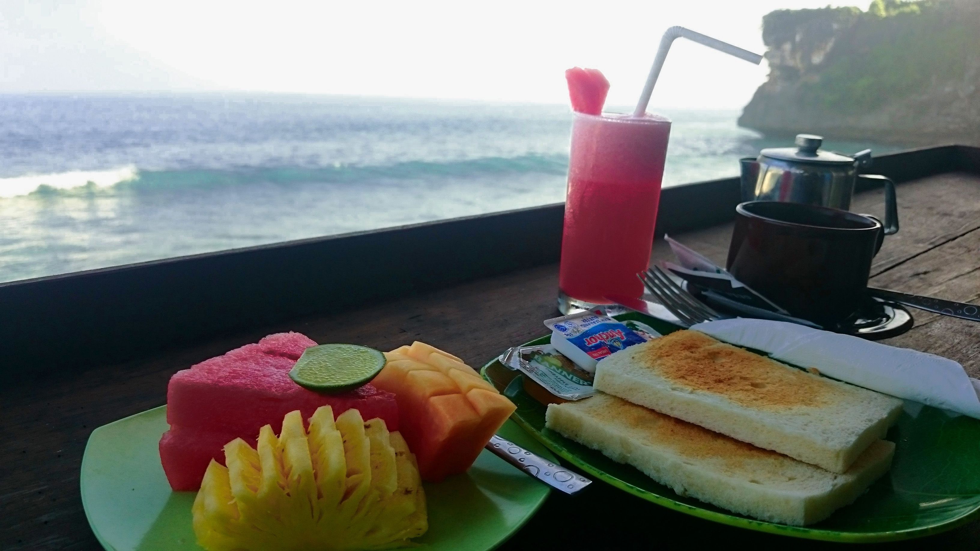 A meal with a drink and a view of the ocean.