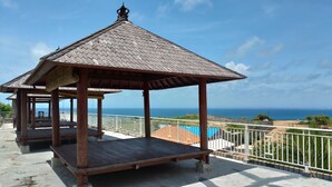 A wooden gazebo with a tiled roof overlooking a beach and ocean. - Balangan Paradise Hostel and Restaurant (Jimbaran)