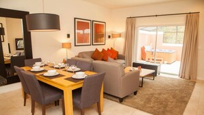 Een moderne woonkamer met een eethoek, een bank en uitzicht op buiten.