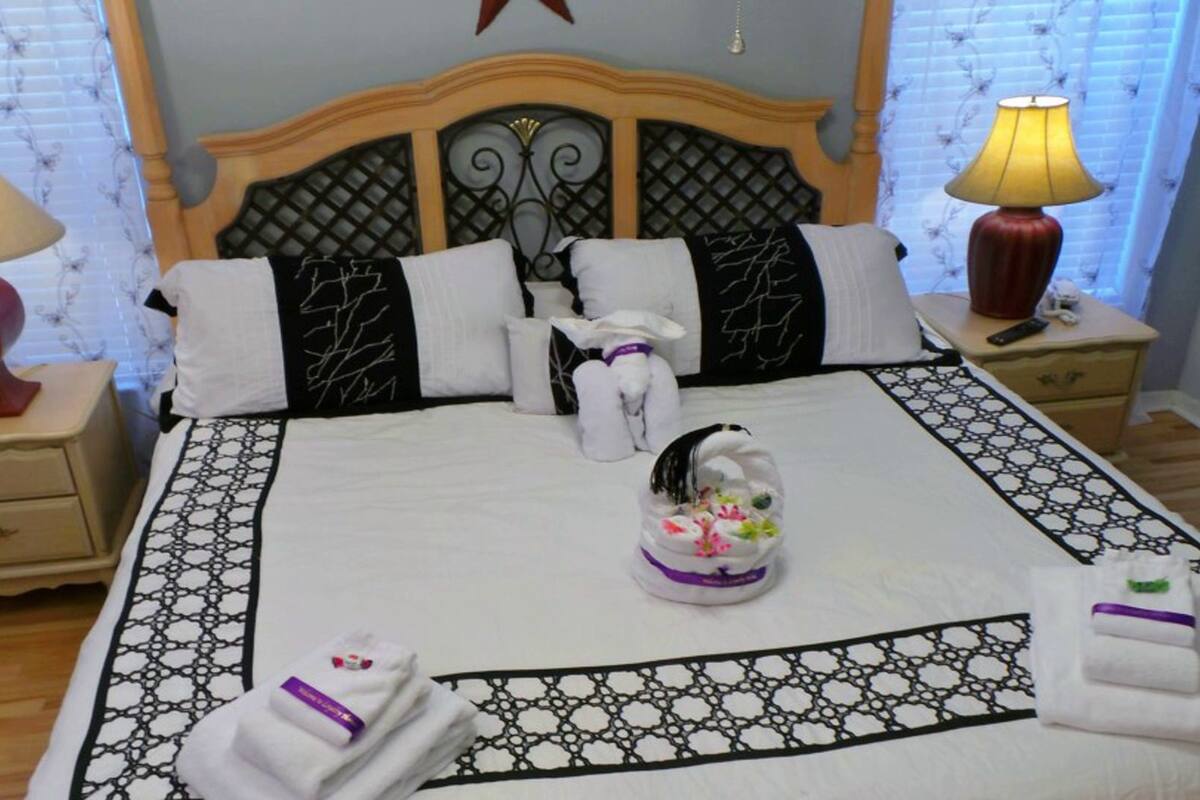A neatly made bed with a patterned bedspread, two bedside lamps, and a decorative pillow.