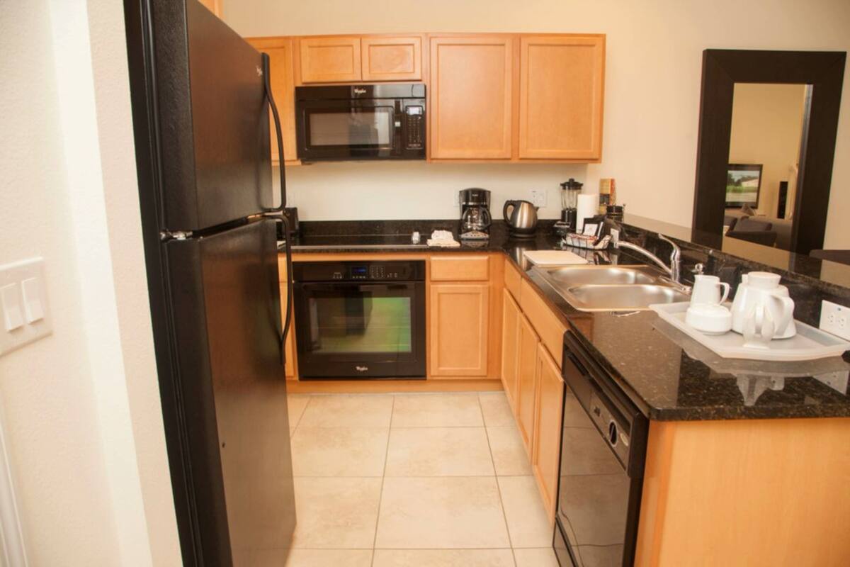 A compact kitchen with a refrigerator, microwave, oven, and coffee maker.
