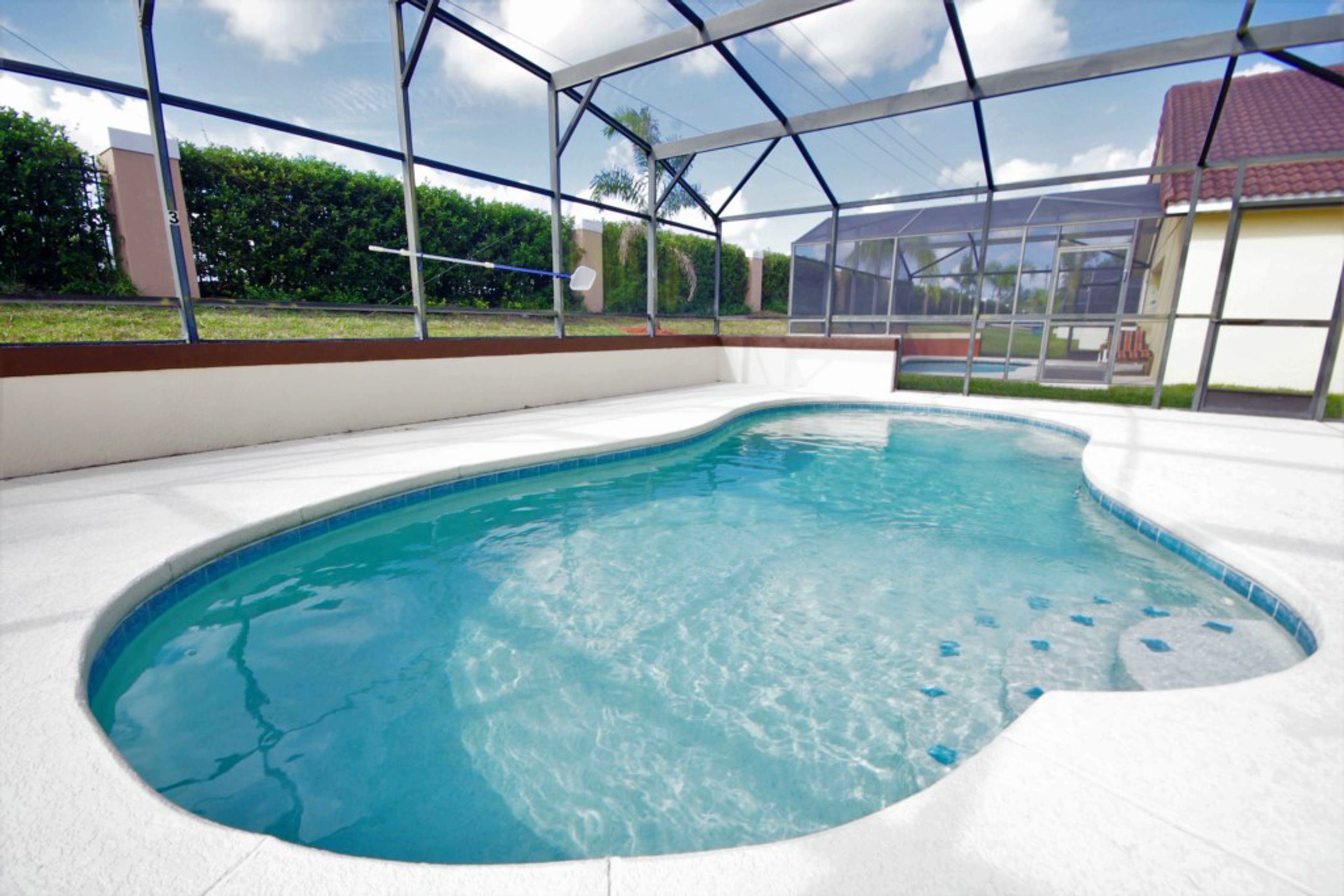 Ein Hallenbad mit klarem, blauem Wasser, umgeben von einem weiß gefliesten Deck und einer Glaskonstruktion.