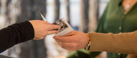 A person handing over a printed document to another person at a counter.