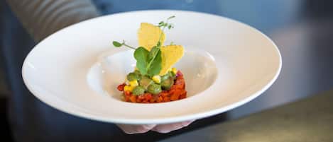 Une assiette blanche contenant un plat, tenue par une personne.