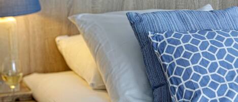 A bed with white and blue patterned pillows, a wooden nightstand with a glass, and starfish decorations.