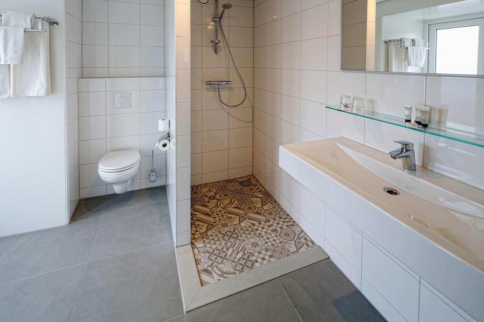 Un baño moderno con ducha, inodoro y tocador.
