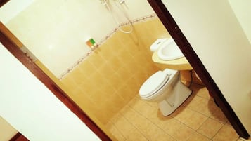 Un baño con dos inodoros, una ducha y suelo de baldosas.