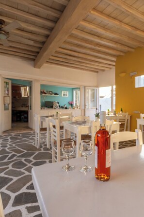 A dining area with a table, two wine glasses, and a bottle of wine. - Alexandra Suites & Rooms - MYKONOS PORT (Mykonos)