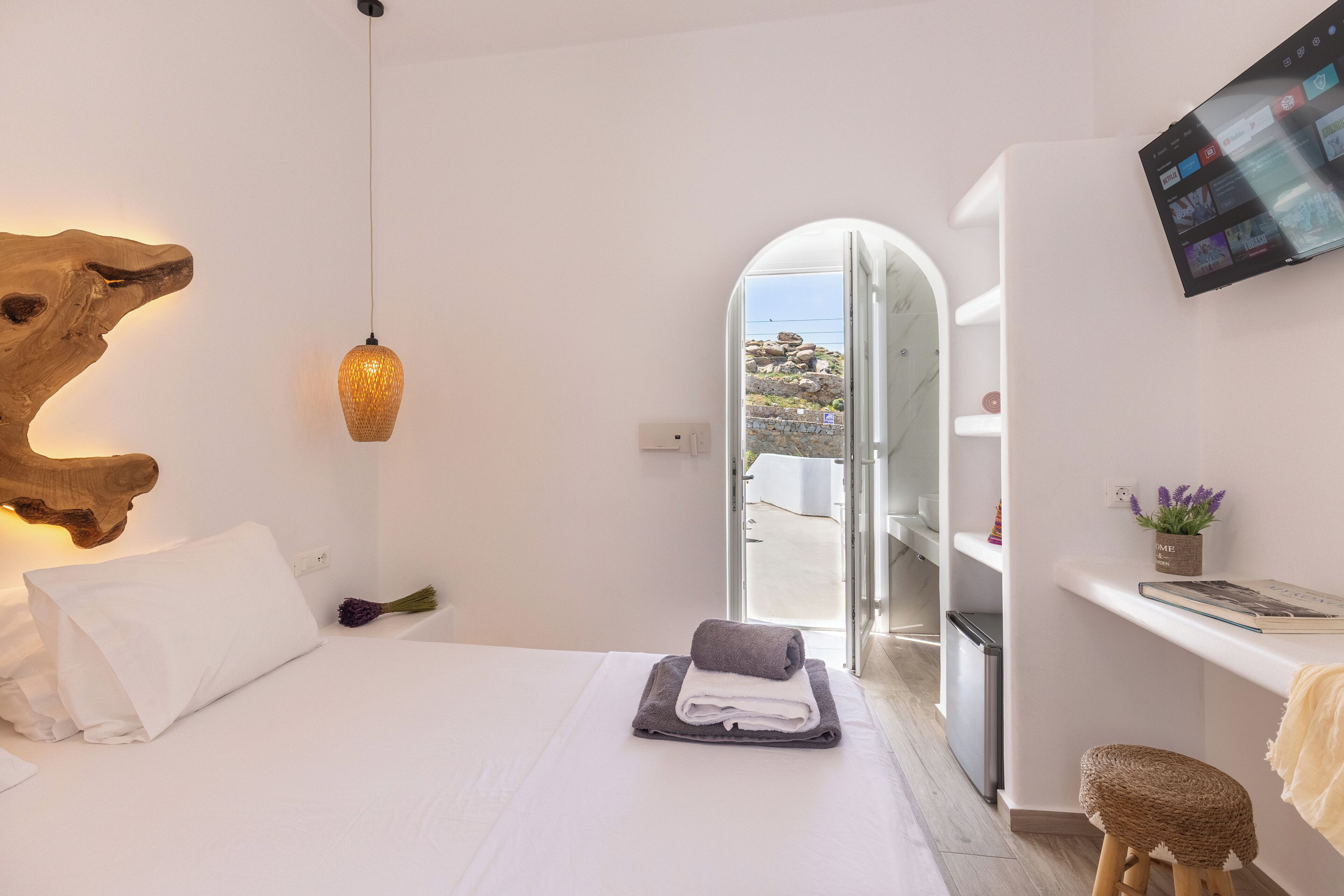 Une chambre à coucher moderne avec un lit, un téléviseur et une vue sur l’extérieur.