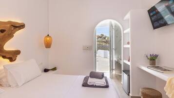 Ein modernes Schlafzimmer mit Bett, Fernseher und Blick ins Freie.