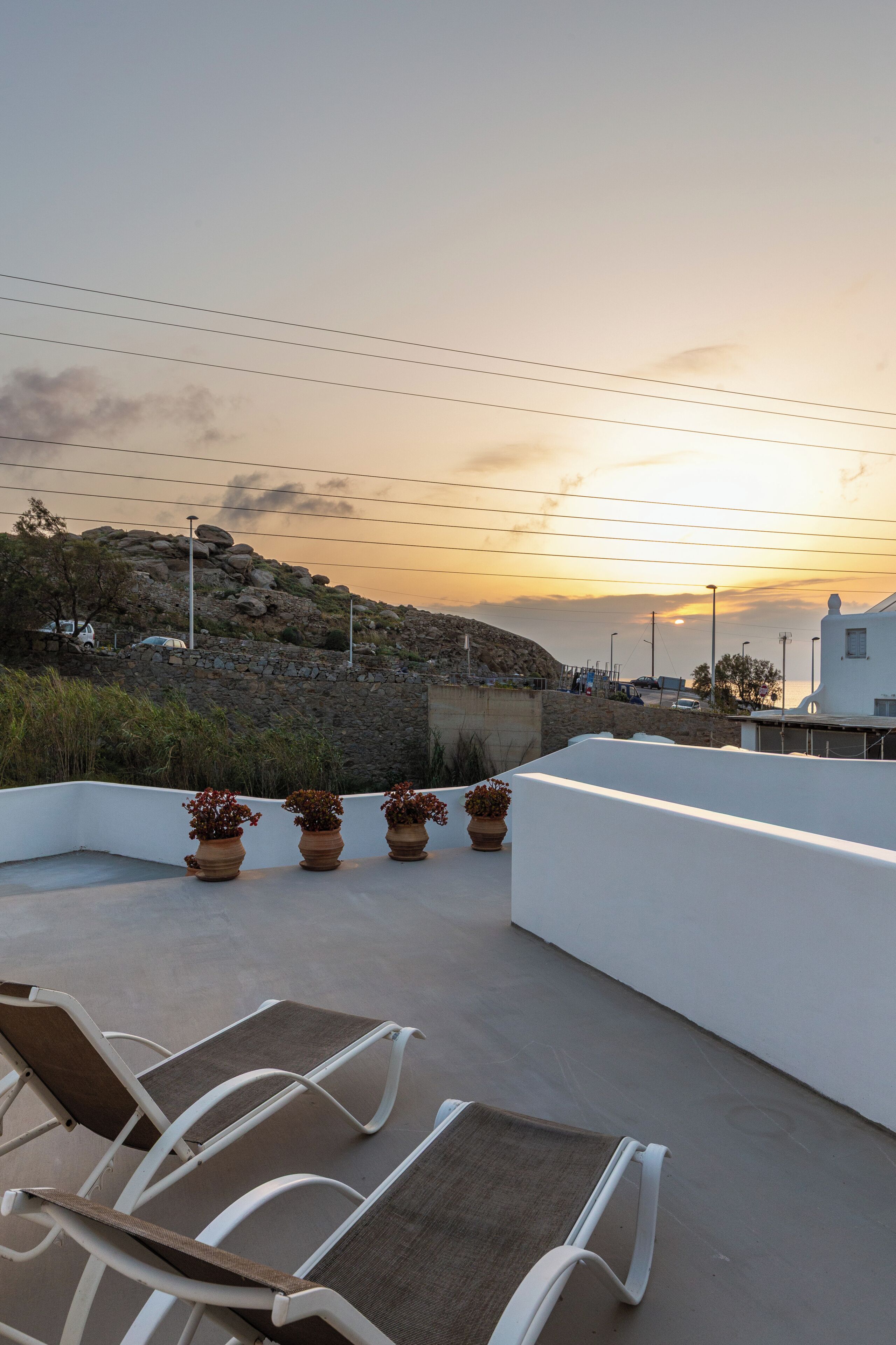 Eine Dachterrasse mit Sitzgelegenheiten im Freien und Blick auf den Sonnenuntergang.