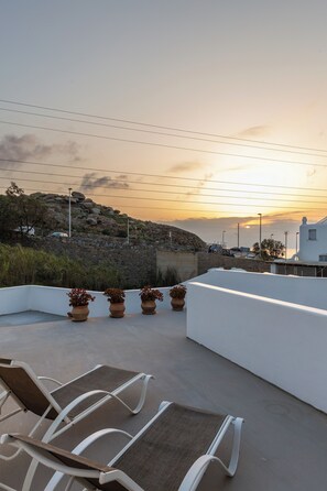 A rooftop terrace with outdoor seating and a view of the sunset.