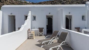 A rooftop terrace with white walls, a seating area with lounge chairs, and a view of the surrounding landscape.