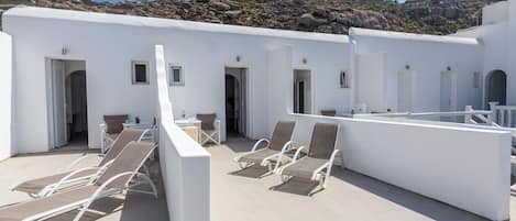 A rooftop terrace with white walls, multiple doors, and outdoor seating.