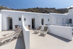 A rooftop terrace with white walls, multiple doors, and outdoor seating.