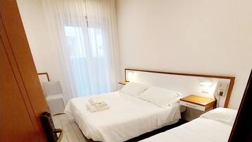 A hotel room with two beds, a bedside table with a lamp, a phone, and a sign indicating room number 406.