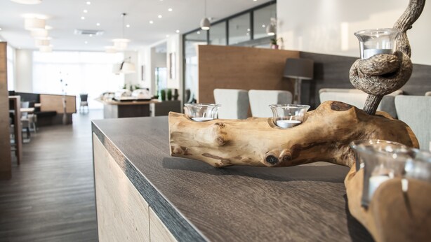 Un centro de mesa de madera con jarrones de cristal sobre una encimera en un interior moderno.