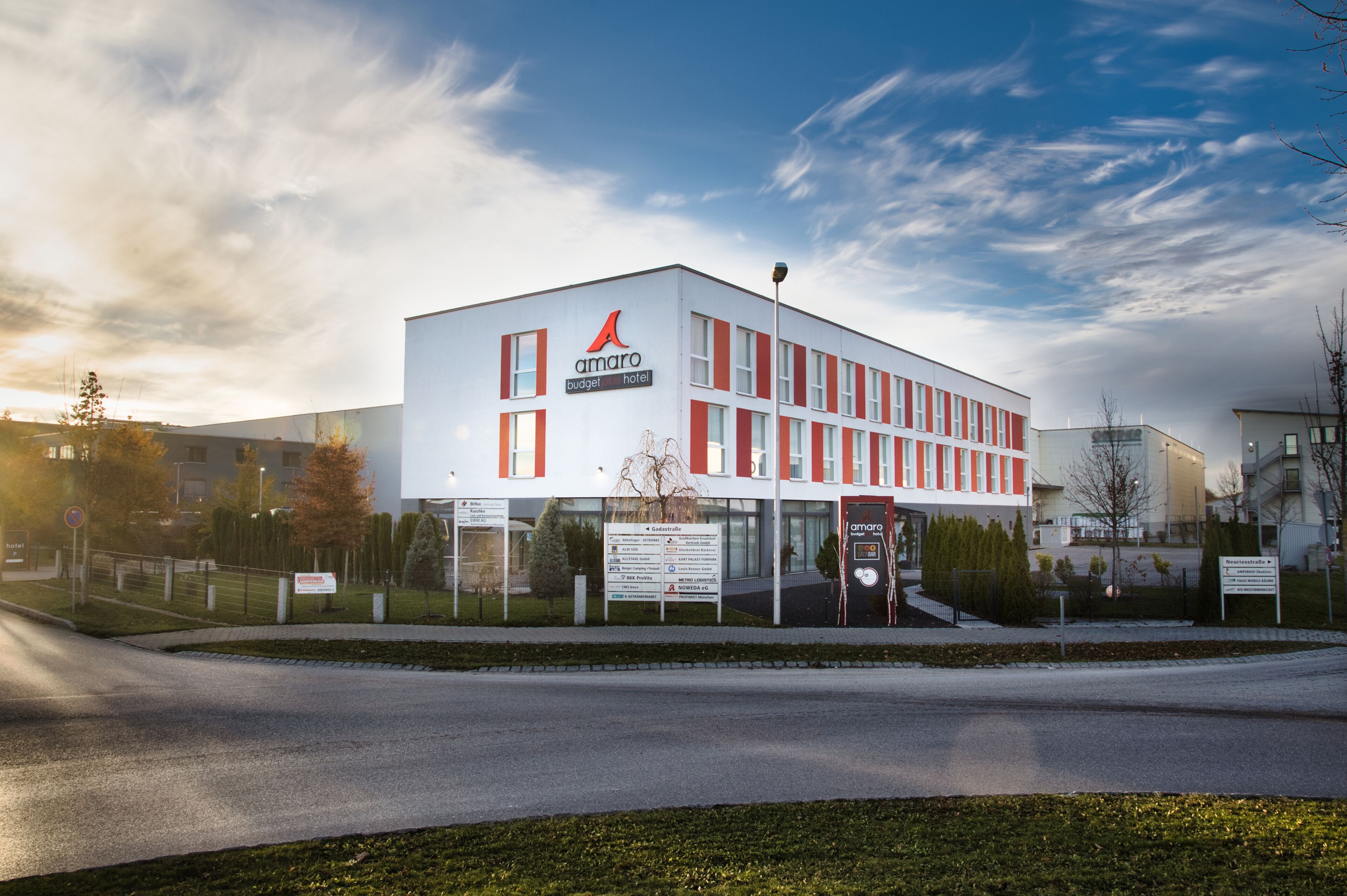 A modern building with a white facade and red accents, labeled as 'Amaro Budget Hotel'.