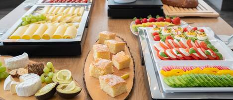 A buffet with various food items including cheese, bread, and fruit.