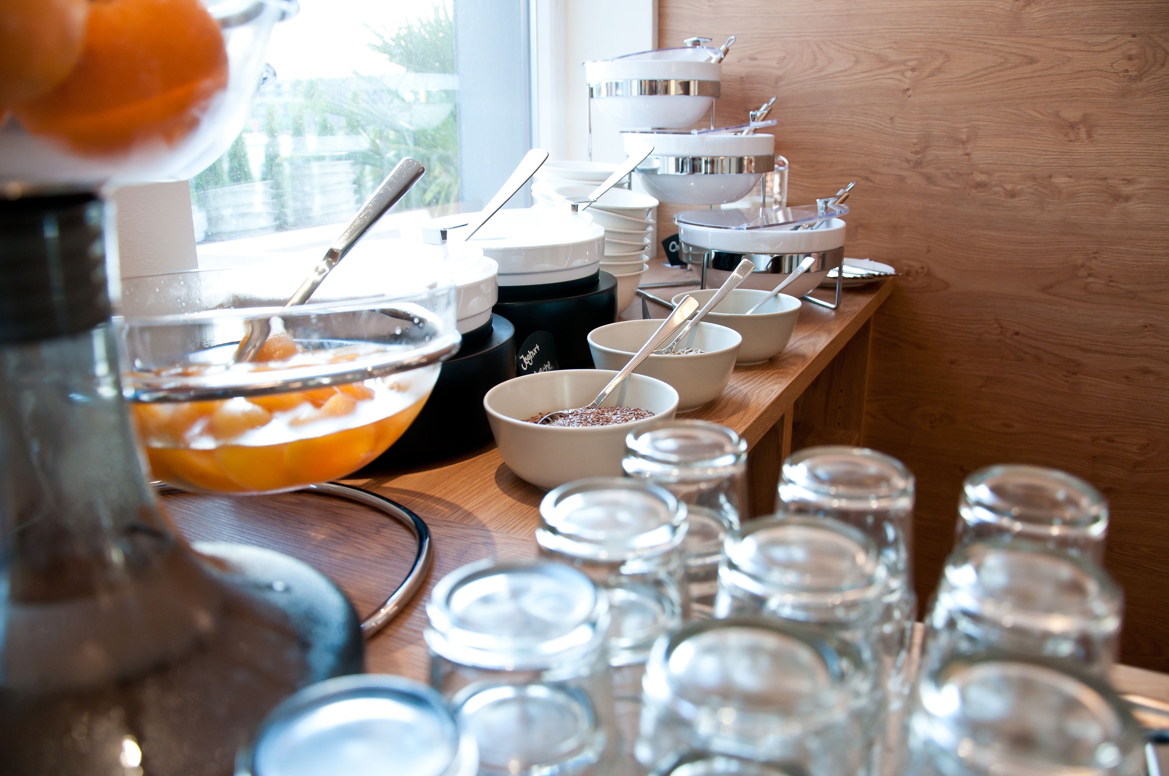 Ein reichhaltiges Buffet mit verschiedenen Schüsseln, Löffeln und Gewürzbehältern auf einem Holztisch.