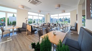Un restaurante espacioso con amplios ventanales, varias zonas de estar y una decoración moderna.