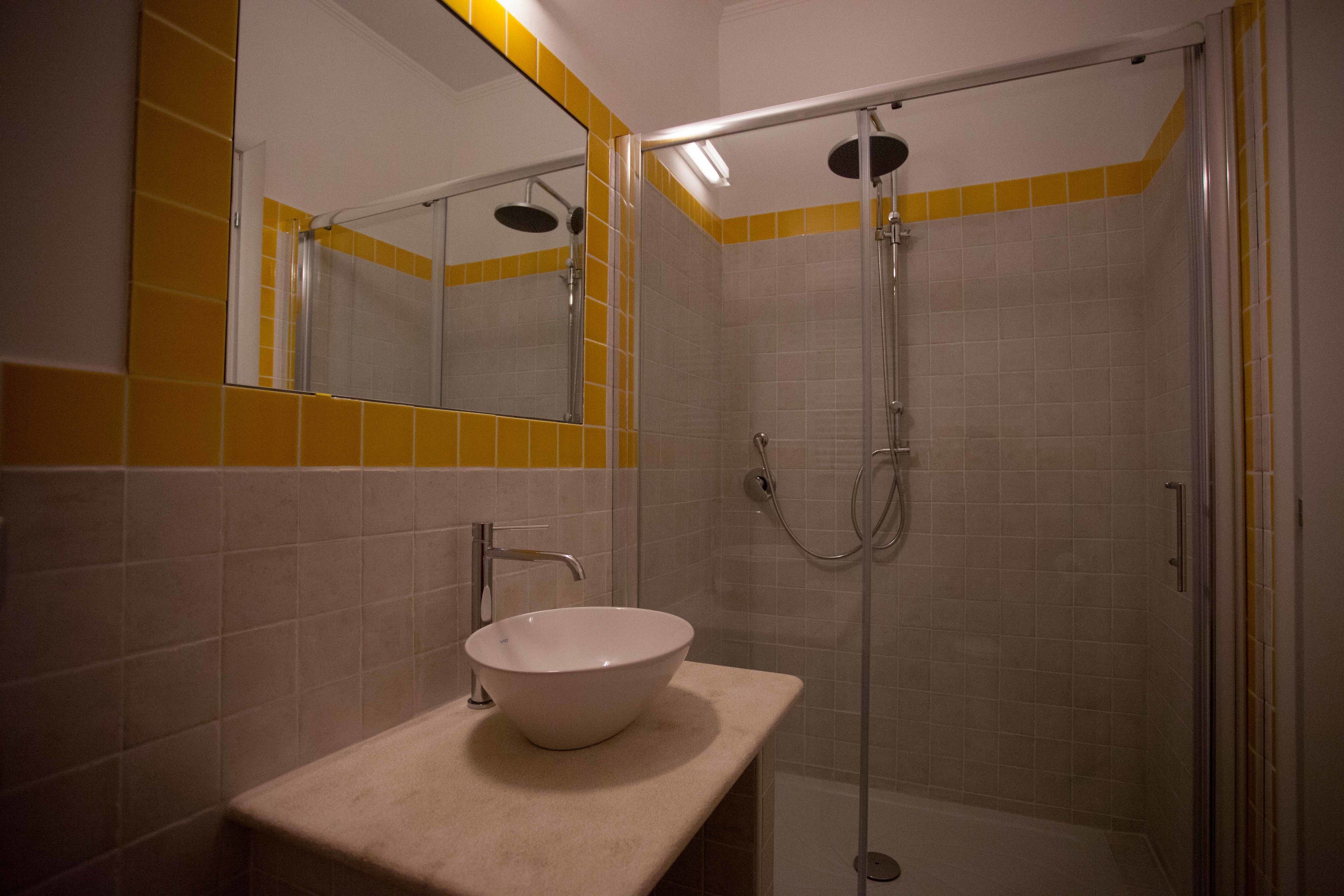 A bathroom with a white sink, a mirror, and a shower enclosure.