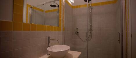 A bathroom with a white sink, a mirror, and a shower enclosure.