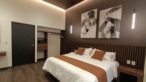 Une chambre d’hôtel moderne avec un grand lit, une armoire, une table de chevet et des œuvres d’art abstraites accrochées au mur.