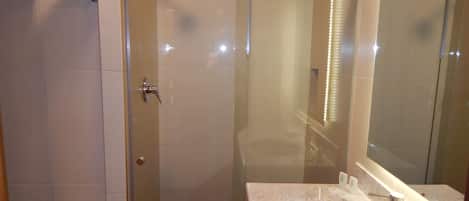 Un baño moderno con ducha de vidrio, lavamanos de mármol y un espejo grande.