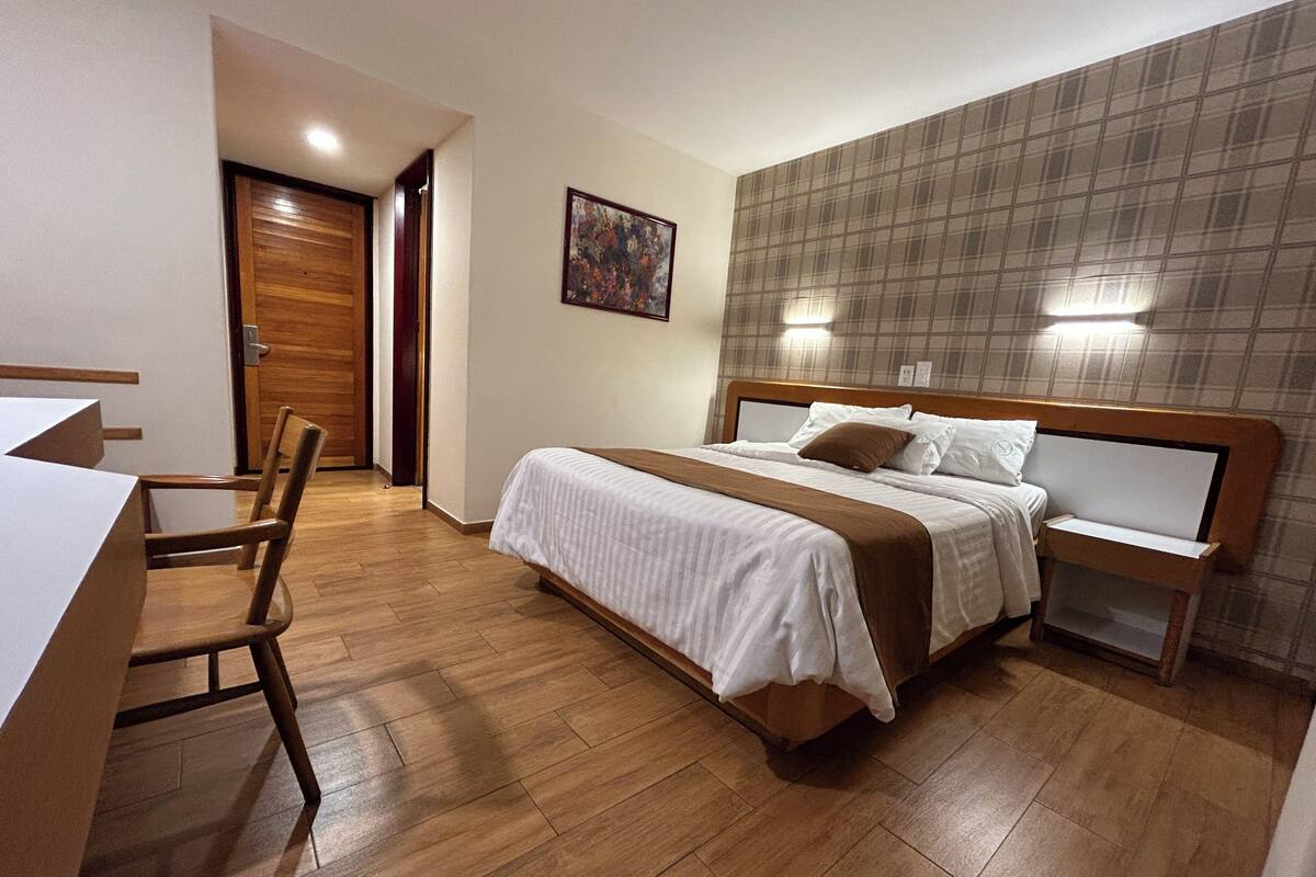 Une chambre d’hôtel avec un lit en bois, un bureau et une chaise.
