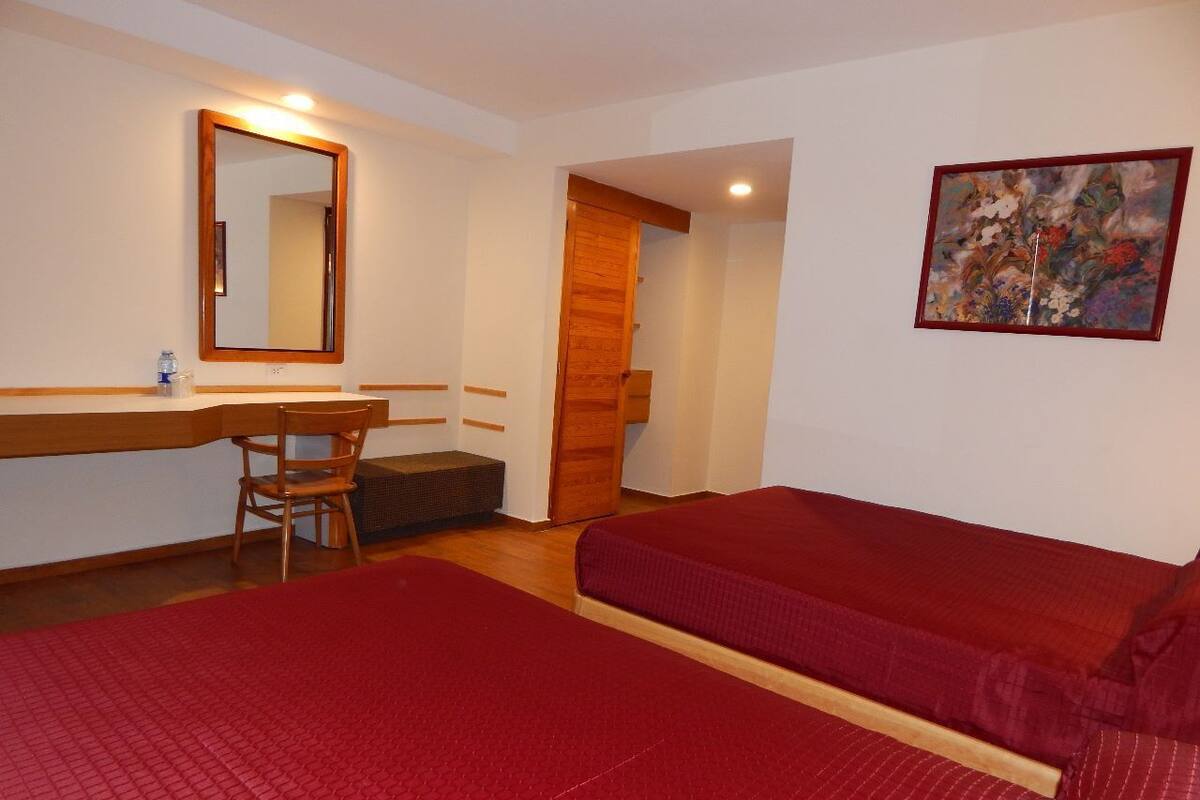 Une chambre d’hôtel avec deux lits, un bureau, une chaise, un miroir et un tableau au mur.