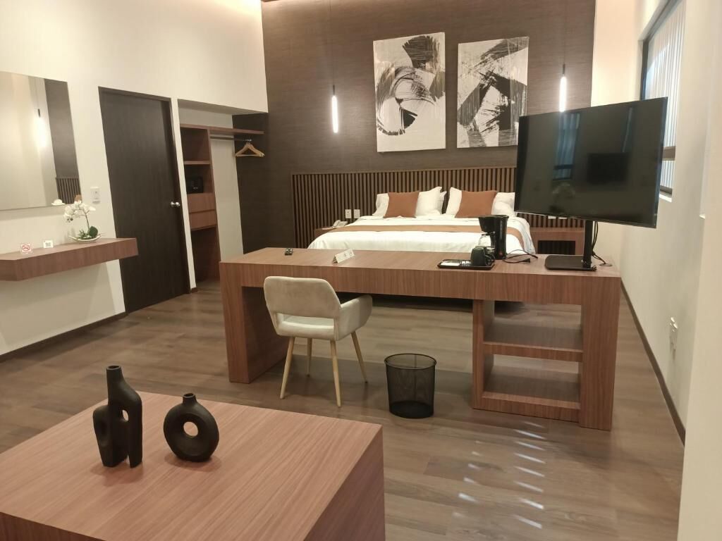 Una habitación de hotel moderna con cama, mesita de noche, televisión y escritorio con silla.