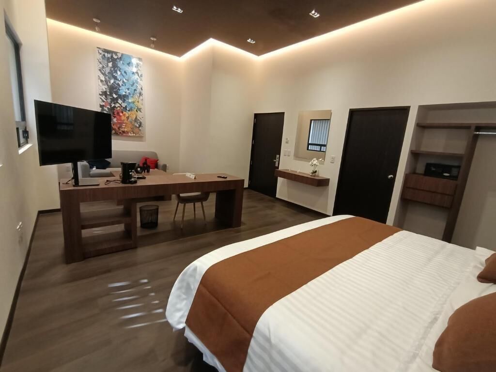 Habitació d'hotel moderna amb llit, escriptori i televisió.