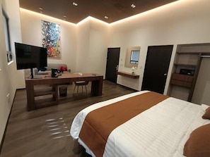 A modern hotel room with a bed, desk, and television.