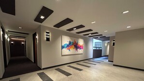 Un couloir moderne agrémenté de panneaux de signalisation, d’un tableau abstrait aux couleurs vives et d’un motif géométrique sur le sol.