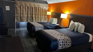 A hotel room with two beds, a desk, and a television.