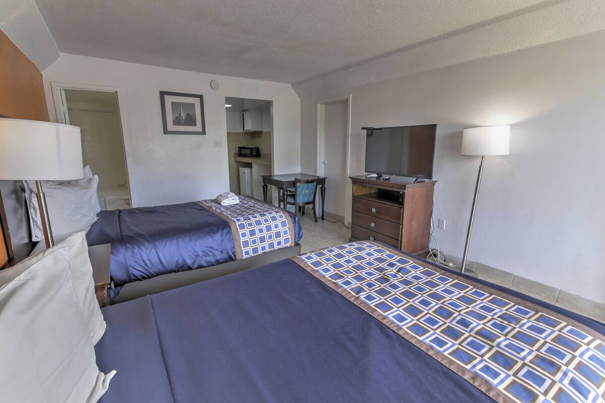 A hotel room with two beds, a desk, a television, and a wardrobe.