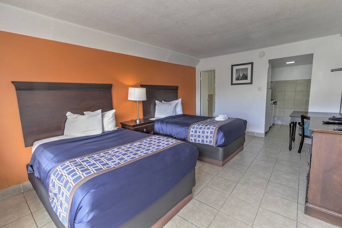 A hotel room with two beds, a desk, and a chair.