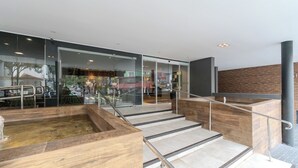 A modern indoor staircase with glass railings and a wooden bench area.