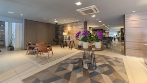 A modern hotel lobby with a round table, seating area, and decorative plants.