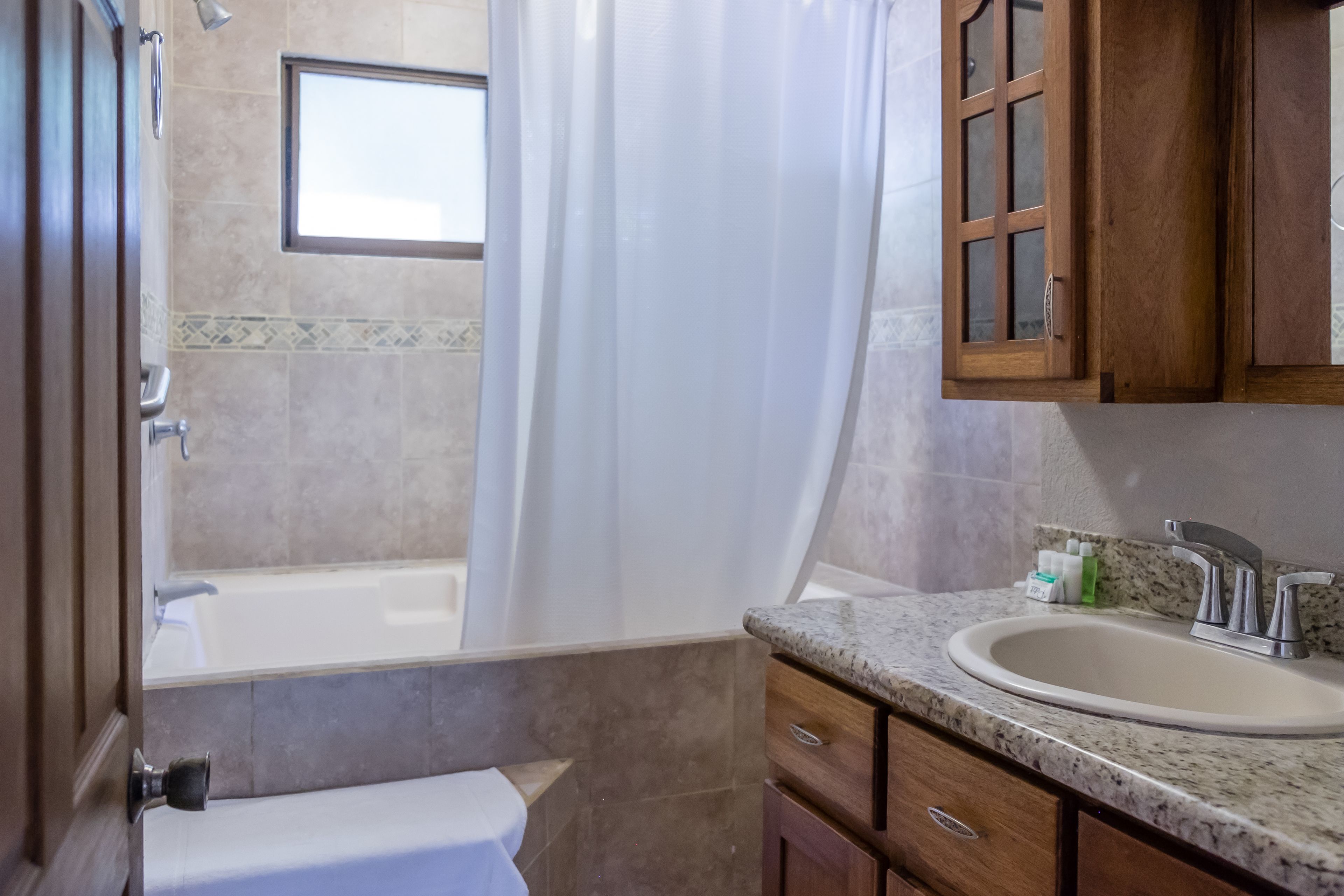 A bathroom with a bathtub, a sink, and wooden cabinets.
