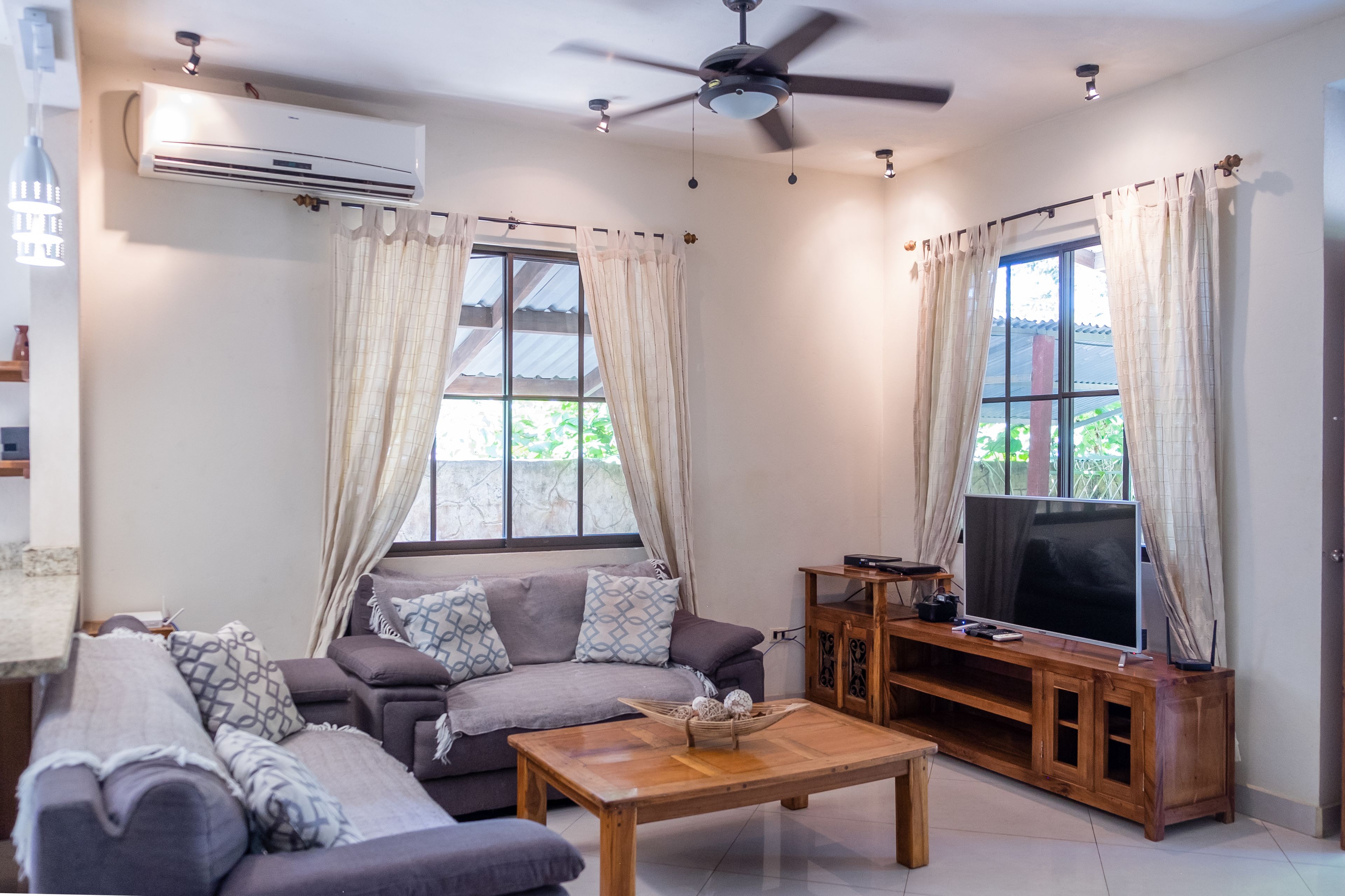 A living room with a sofa, coffee table, TV stand, and curtains.