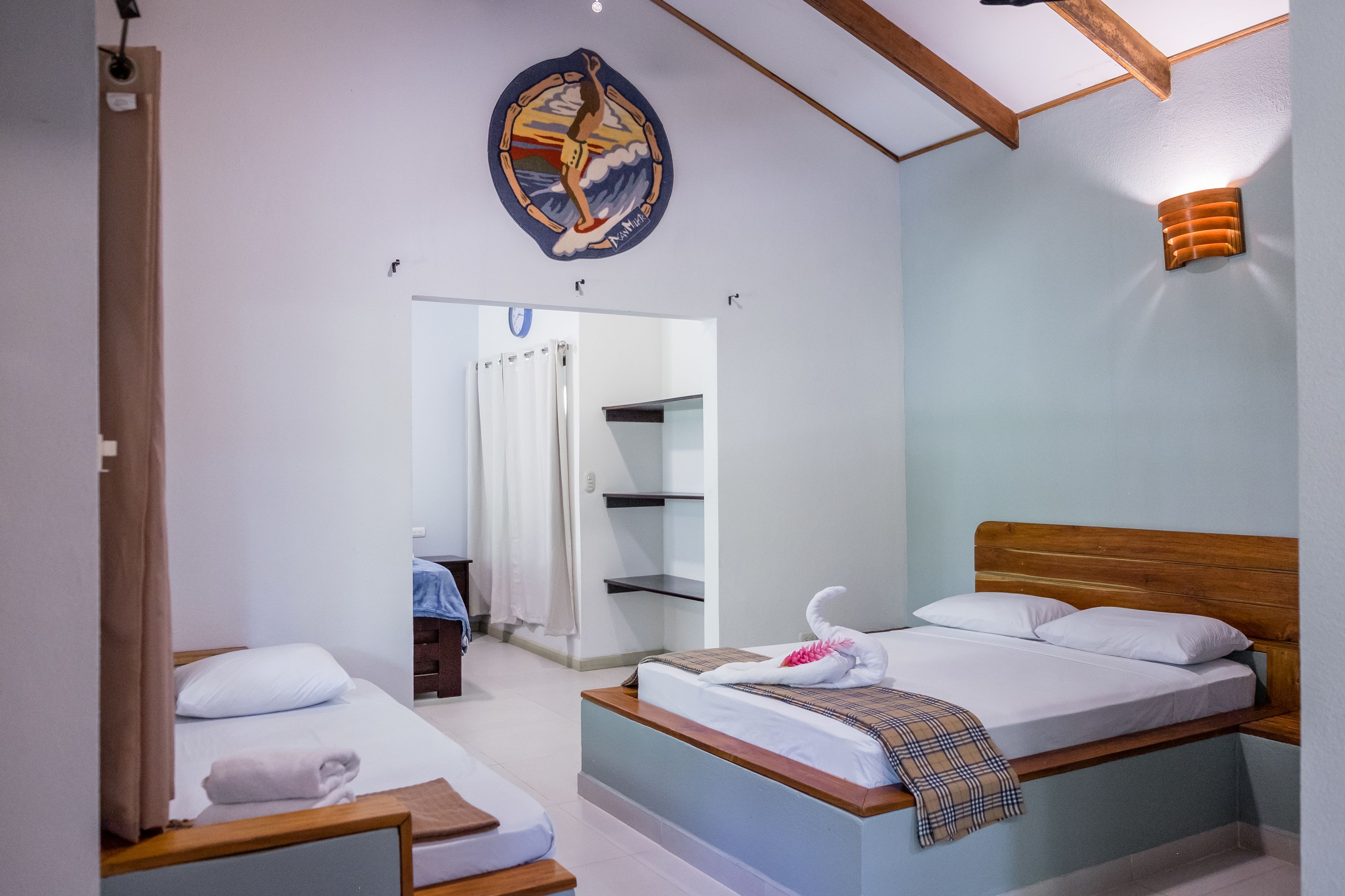 A hotel room with a bed, a small desk, and a shower area.