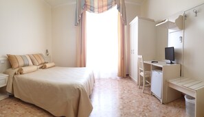 A bedroom with a bed, a desk, a chair, a wardrobe, and a television. - RS San Sebastiano Holidays (Acireale)