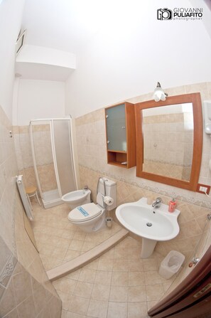 A bathroom with a shower, toilet, bidet, sink, and a mirror. - RS San Sebastiano Holidays (Acireale)