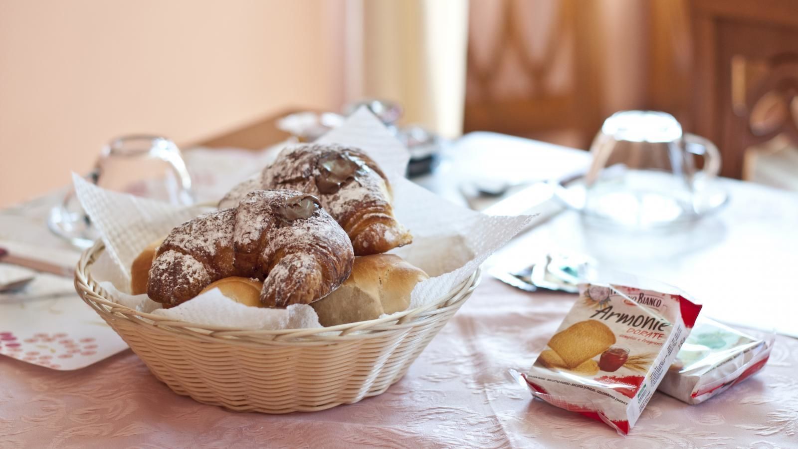 Una cesta de mimbre llena de pasteles sobre una mesa con juego de té.